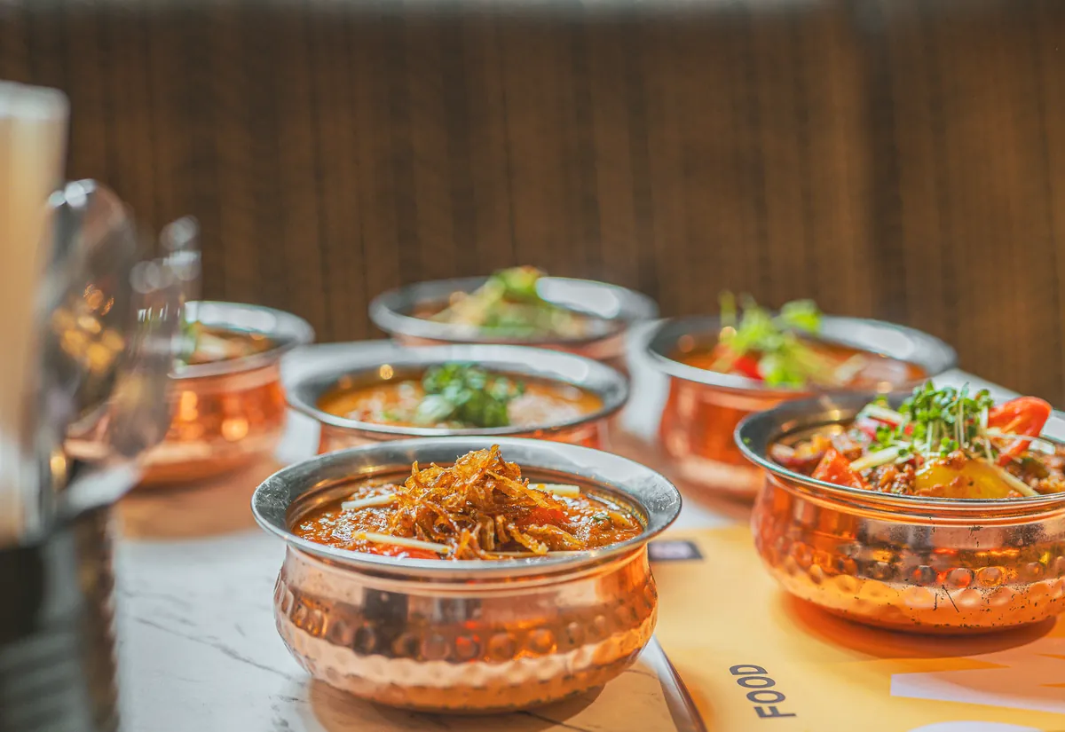 Curries in hammered copper pots, served on a marble table