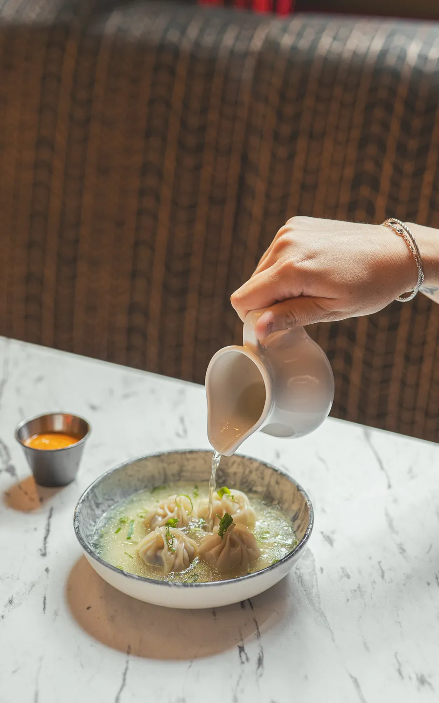 Broth being poured over a bowl of momos